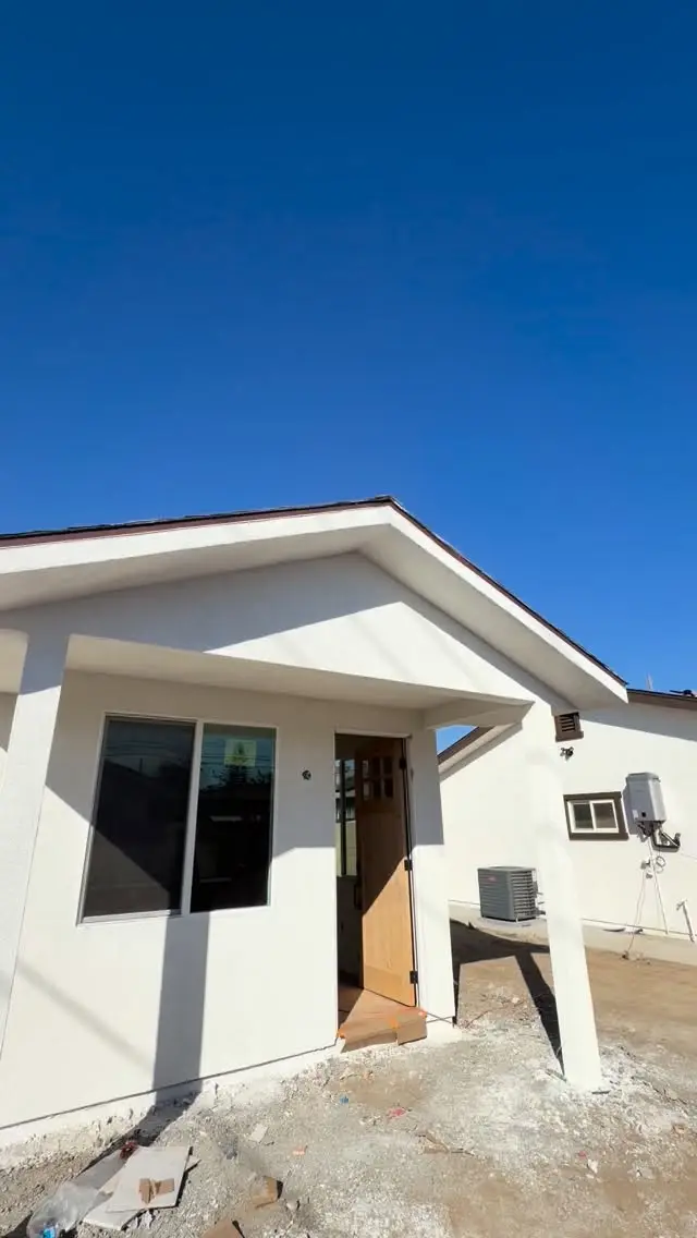 White stucco ADU with a wood front door