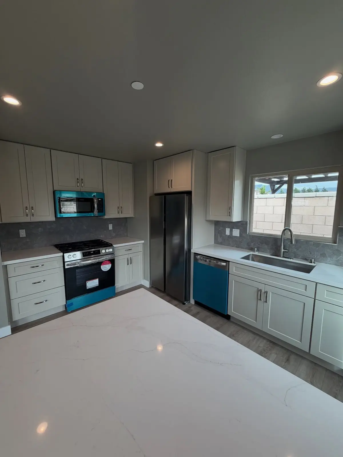 Finished ADU kitchen with gray cabinets and quartz counters