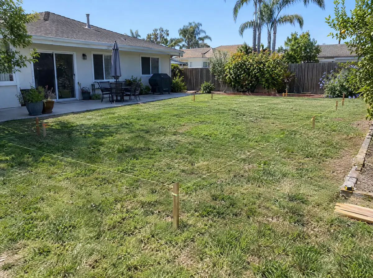 Backyard of a California single-family home with string lines and wooden stakes marking a future ADU footprint on the grass