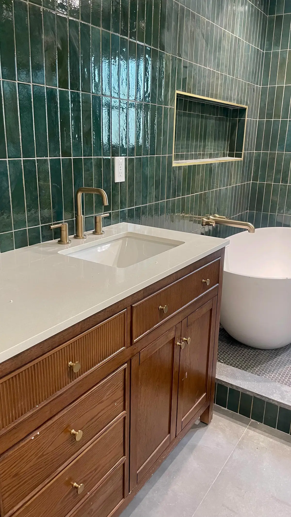 Bathroom vanity with green tile and brass fixtures