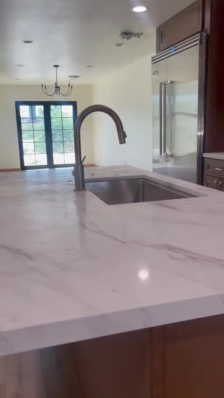 Home addition with a new primary suite in Fontana, CA: kitchen island with an undermount sink facing french doors
