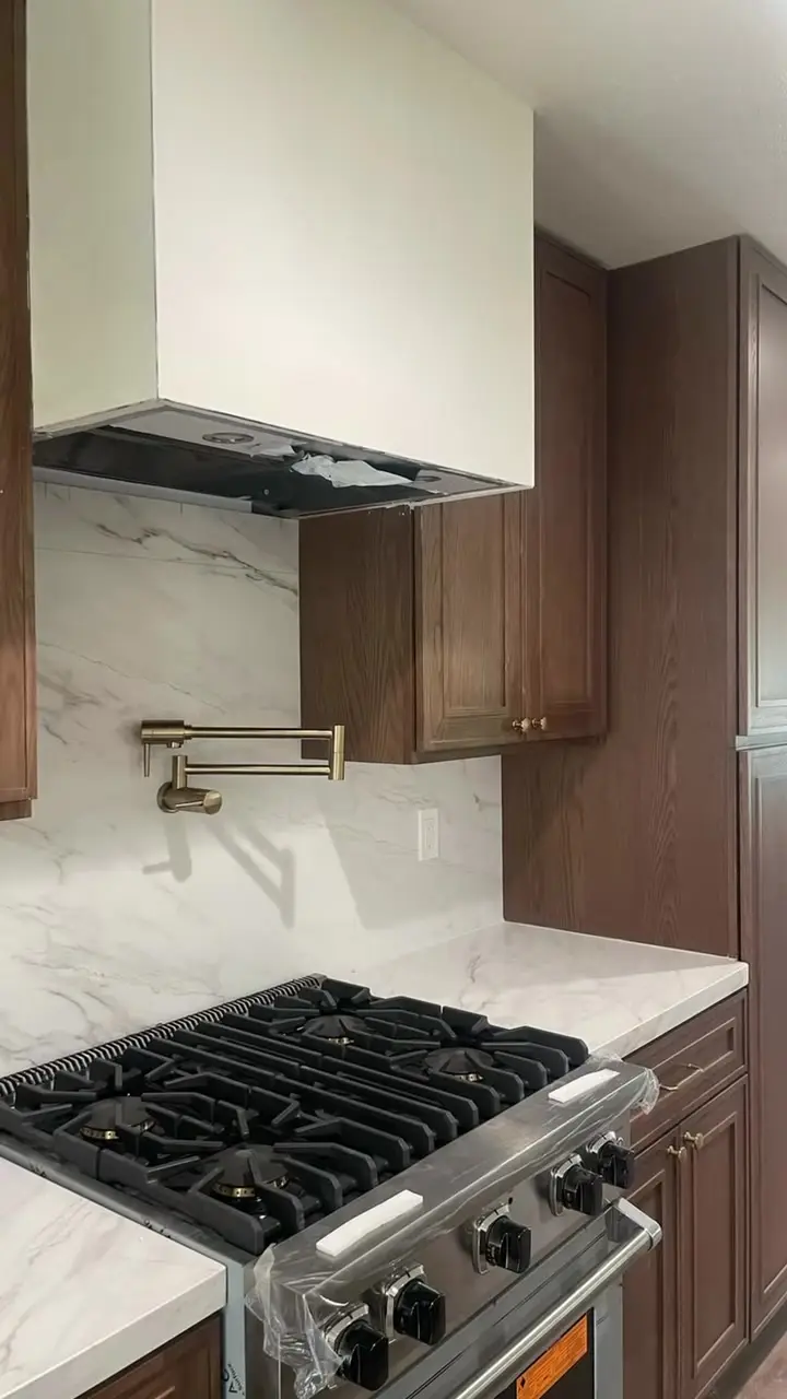 Viking range with a brass pot filler under a plaster hood