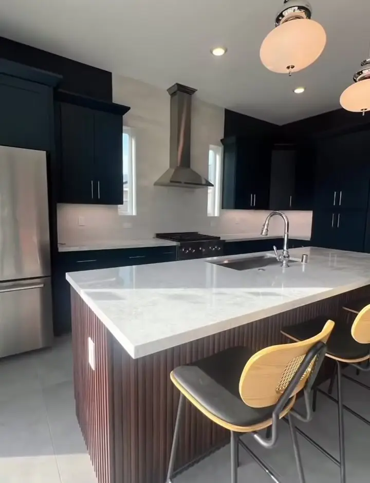 Navy kitchen with a white waterfall island and bar stools