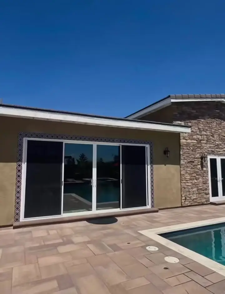 Pool house ADU with sliding doors beside a backyard pool