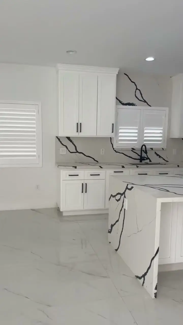 Custom home with a glass garage door in Whittier, CA: white kitchen island and plantation shutters in a new custom home