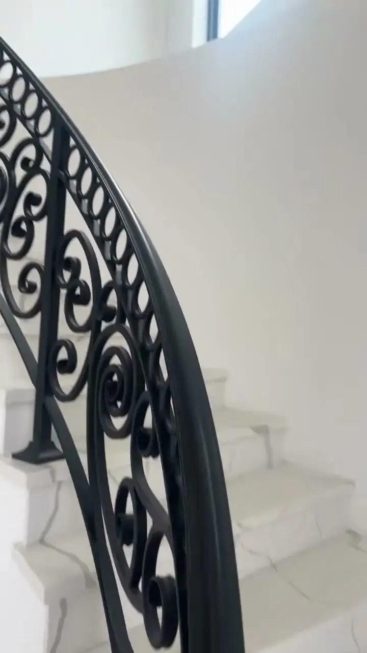Curved wrought-iron stair rail on marble steps